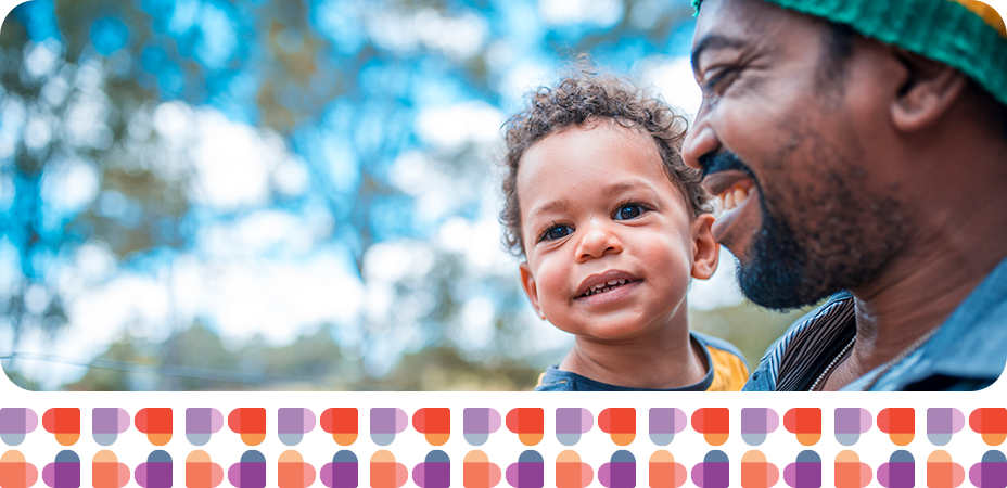 Man holding son smiling in the woods